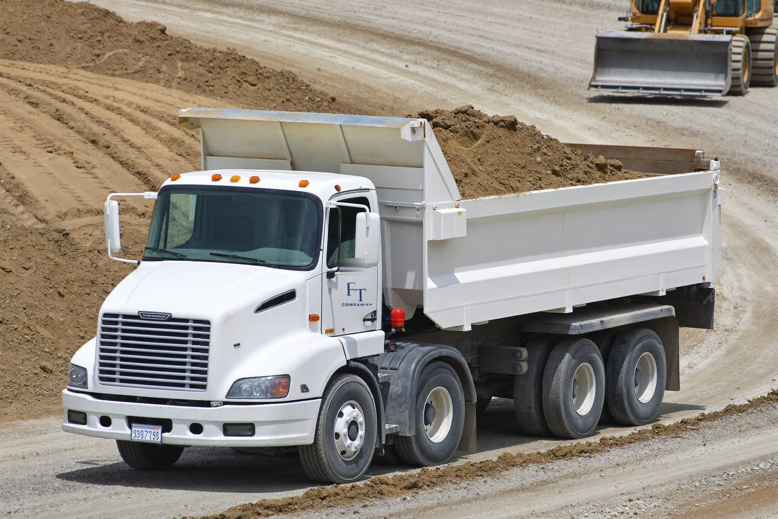 Loaded dump truck on a gravel haul road across a commercial site