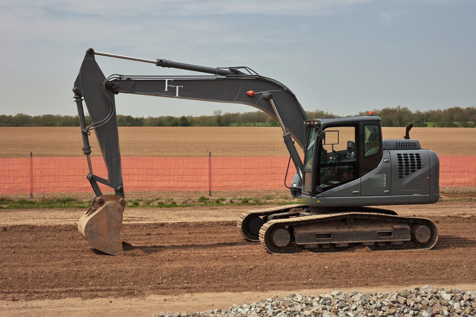 Excavator cutting a building pad behind a silt fence line